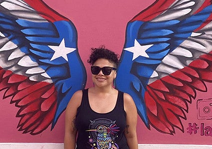 image of Alison Cerezo standing against a wall with painted red white and blue wings