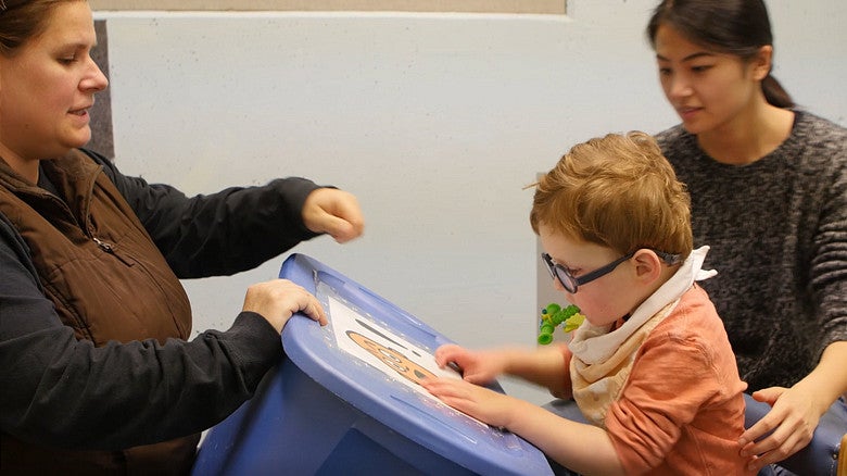 image of two individuals sitting and working with a younger student