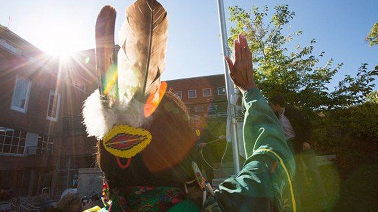 Image of an individual in front of UO building in decorated hat with feathers