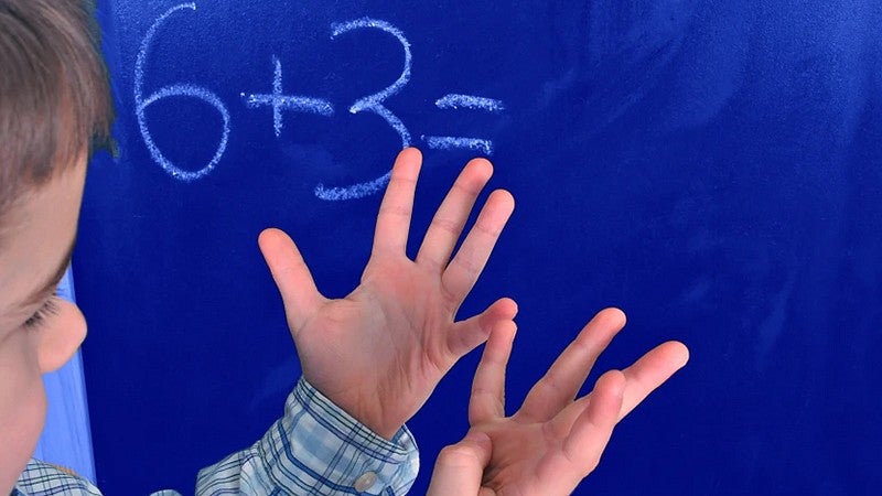 image of a child adding six plus three using their hands