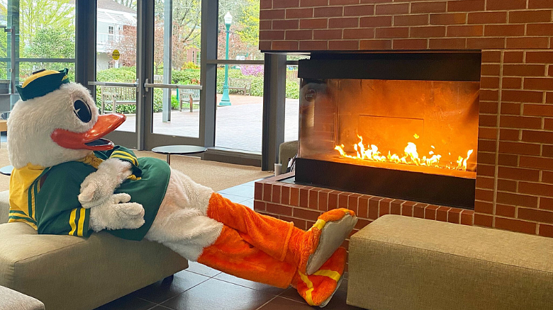 image of the UO Duck sitting by the fireplace in HEDCO with his feet up