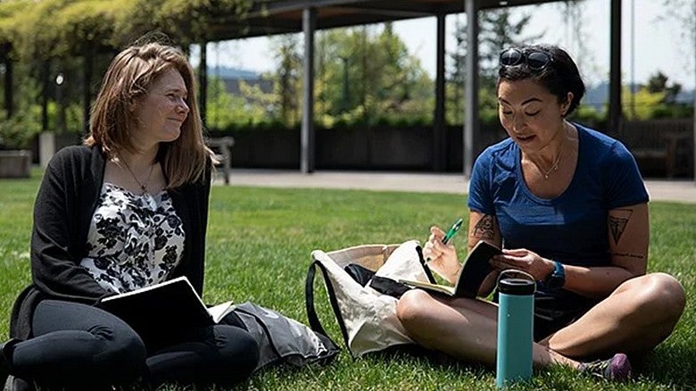 image of two students sitting in the grass outdoors in HEDCO