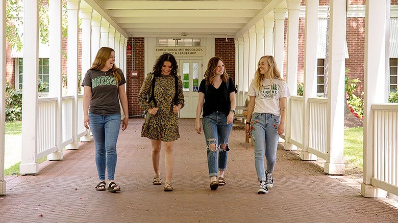 image of four students walking down an outside breezeway