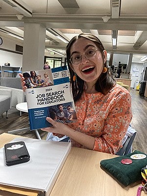 image of T. Acosta holding a job search handbook for educators