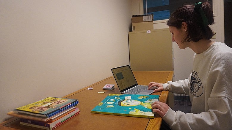 image of person sitting at table looking at a book