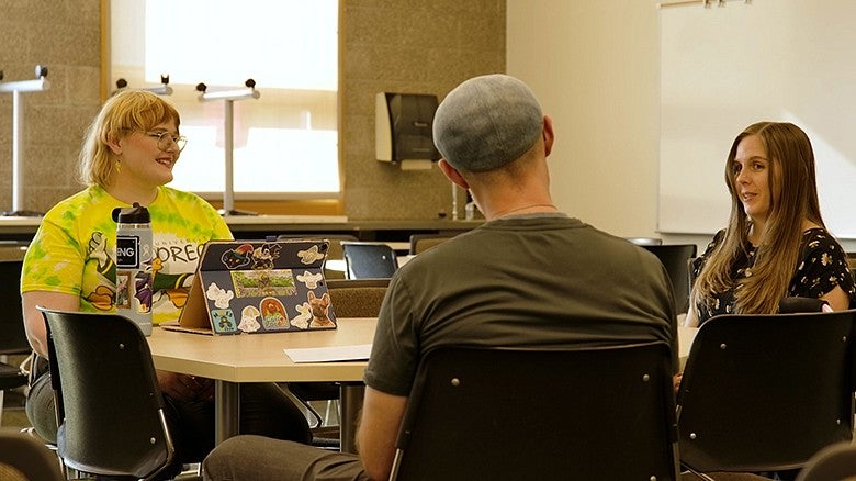 image of three students sitting at a table talking