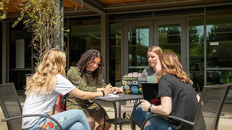 COE students sitting at a table outside of the HEDCO building talking