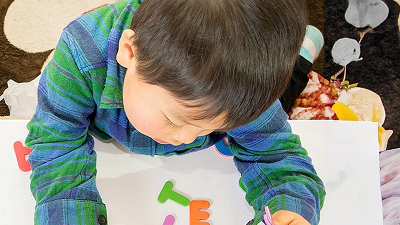 young person sitting at a table playing with plastic letters