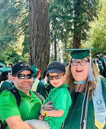 individual posing with two people while dressed in graduation regalia