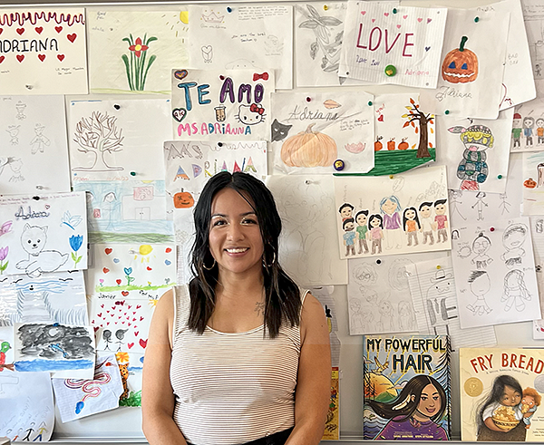 Adriana Alvarez standing in a classroom with children's drawings in the background