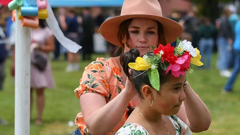 Erika Sauder putting flowers in an individual child's hair during MayDay celebration
