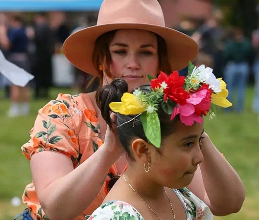 Erika Sauder putting flowers in an individual child's hair during MayDay celebration