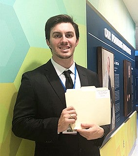 Robert James Konefal holding a manilla folder while smiling at the camera