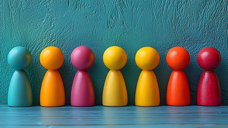 rainbow of human shaped colored blocks placed in a row on a table