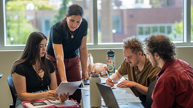 professor teaching college students sitting at a table inside UO Portland campus