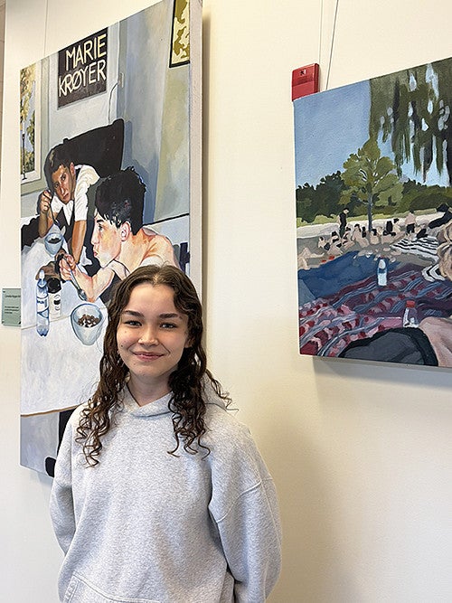 Ava Murakami standing in front of her artwork in the SAS office at the COE