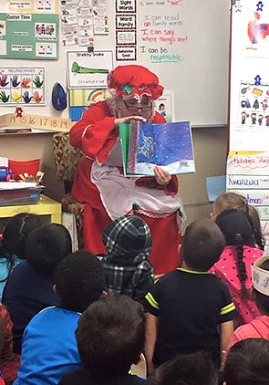 Kate Barker sitting down in a clown outfit reading to a group of children