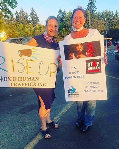 Cati and Marion holding signs while smiling at camera