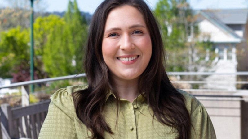 Abbie Sanders in a green blouse standing in the COE HEDCO courtyard