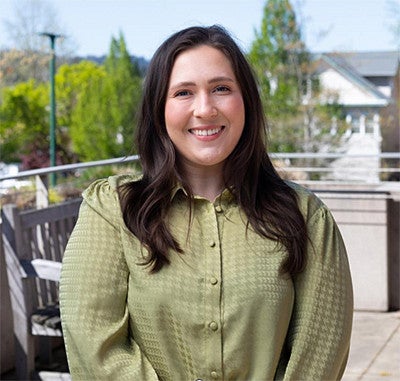 Abbie Sanders in a green blouse standing in the COE HEDCO courtyard