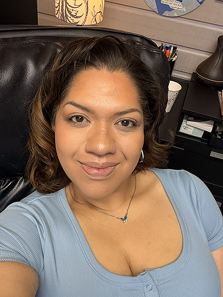 Sarai Santos sitting in a brown leather chair taking a self portrait