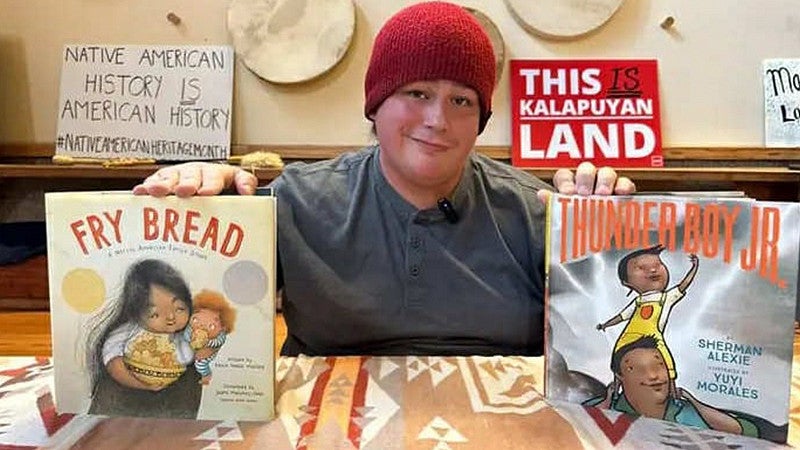 Sage Hatch holding up two books, Fry Bread and Thunder Boy Jr.