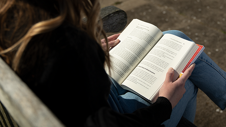 student holding an open book on their lap