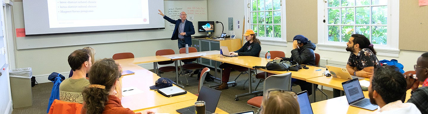 EPoL students in classroom sitting at a shared table while professor teaches