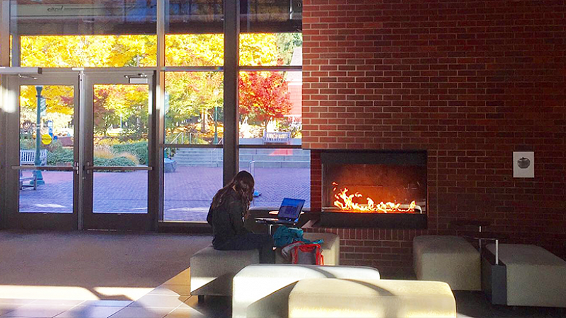 COE student in front of HEDCO Education Building lobby fireplace