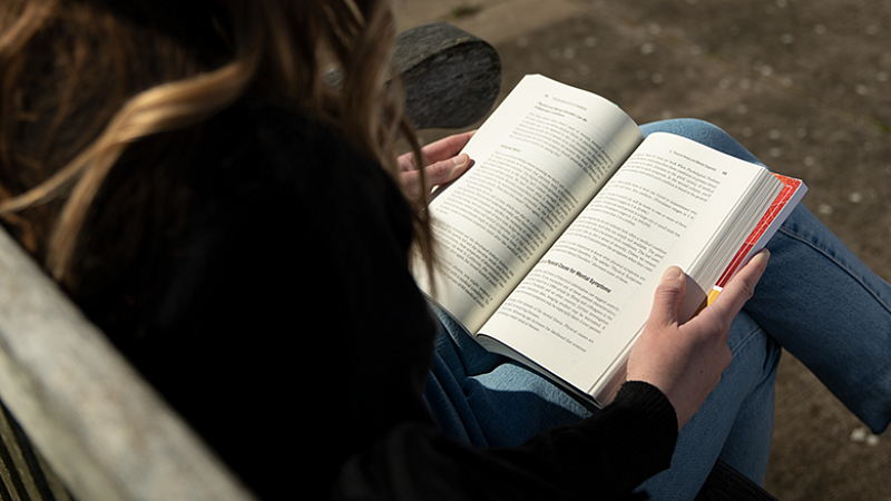 student holding an open book on their lap