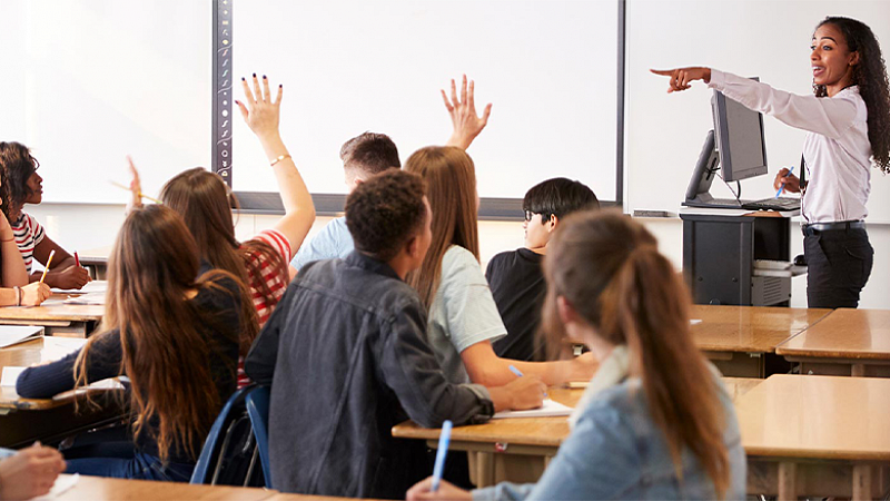 a person pointing in a classroom filled with students