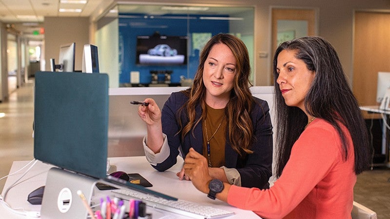 image of two individuals looking at a computer screen