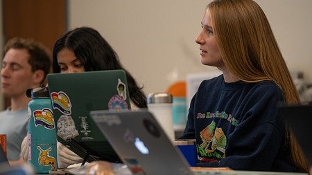 image of students seated in a class environment with laptops open