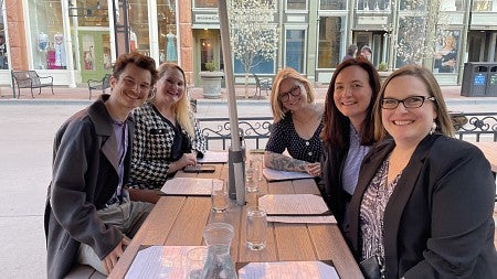 group of individuals sitting at a table smiling at the camera