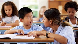 student discussing work on desk with teacher