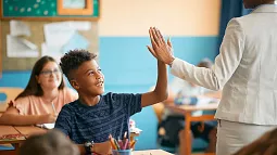 image of a teacher greeting student with a high five