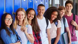 image of a group of young individuals looking towards camera while leaning against school lockers