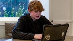 young individual sitting in front of a laptop