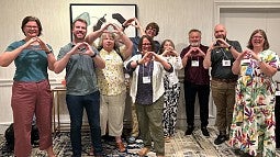 group of COE faculty past and present using their hands to form an O