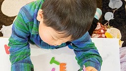 young person sitting at a table playing with plastic letters