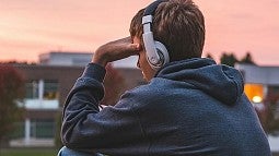 individual in headphones sitting with hand on forehead
