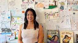 Adriana Alvarez standing in a classroom with children's drawings in the background