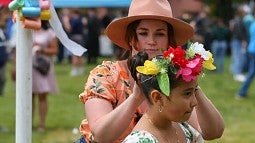 Erika Sauder putting flowers in an individual child's hair during MayDay celebration