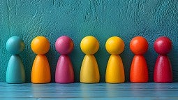 rainbow of human shaped colored blocks placed in a row on a table