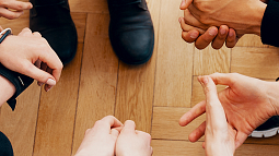 several adult hands clasped together
