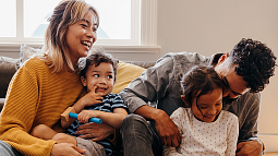 adult and young individuals sitting on a couch laughing