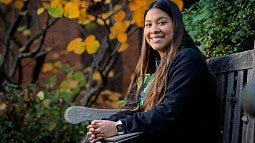 Anahi Cortes sitting on a wooden bench hands in lap smiling at the camera