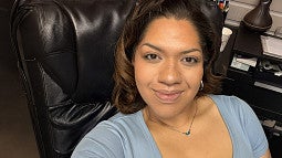 Sarai Santos sitting in a brown leather chair taking a self portrait