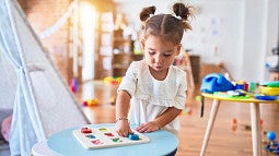 young child playing with a toy while standing at a table