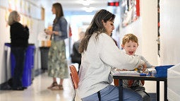 teacher and student at a desk in a school hallway